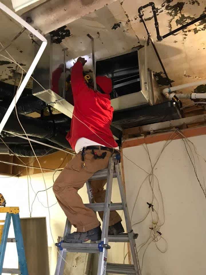 Technician performing air duct cleaning inside ceiling system in Florissant, MO.