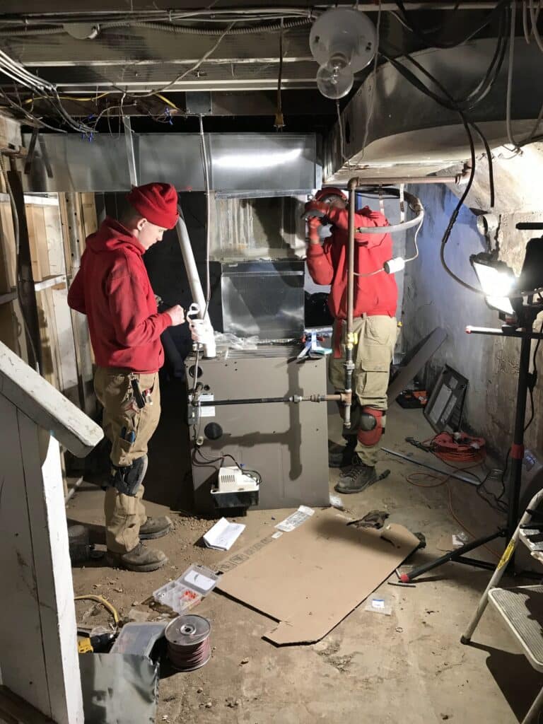 Technicians installing air duct system in basement in Florissant, MO.