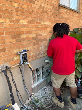 HVAC technician inspecting electrical connections outside home in Duchesne Hills, MO.