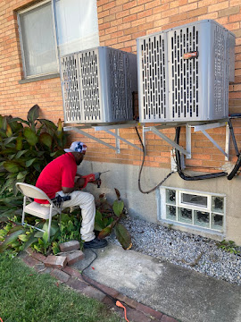 Technician installing outdoor AC units on wall brackets in Riverwood, MO.