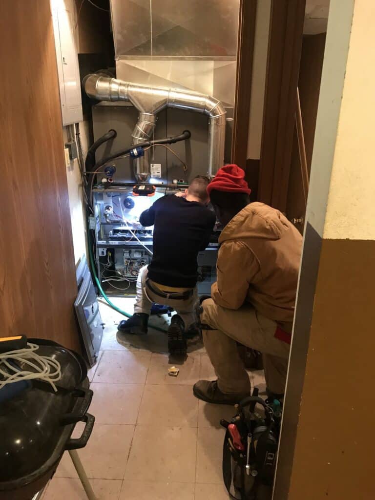 Technician performing heat pump repair inside utility room in Florissant, MO.