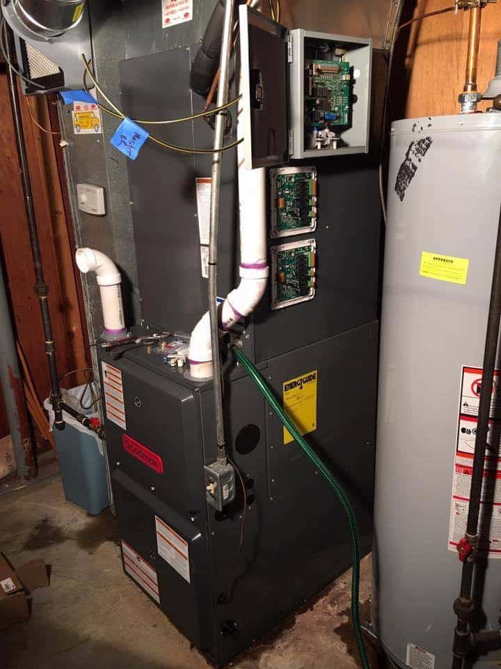 HVAC technician performing furnace maintenance and inspecting control boards in Florissant MO basement
